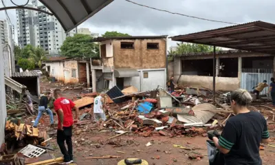 Pessoas entre destroços no pátio da Carrozza Guitars após a enchente.