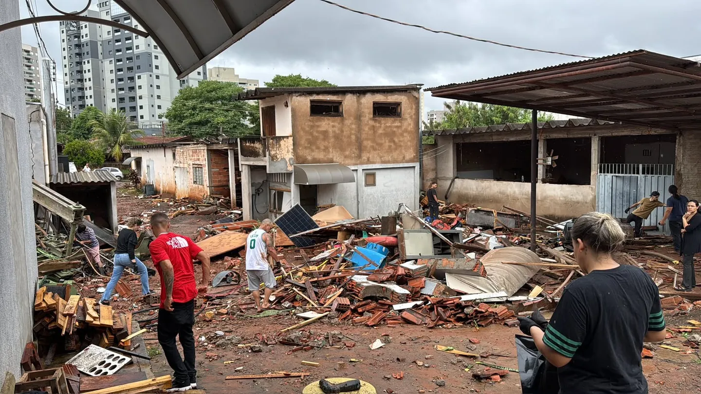 Pessoas entre destroços no pátio da Carrozza Guitars após a enchente.