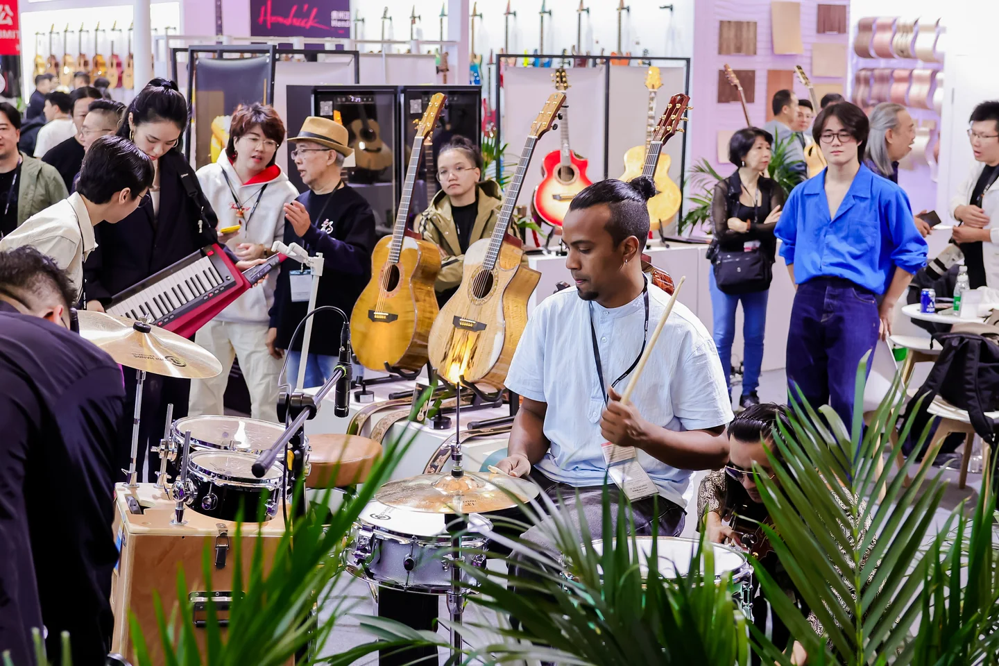 Demonstração de bateria em um estande da Music China 2025 Baterista faz uma demonstração em um estande, cercado por visitantes e instrumentos.