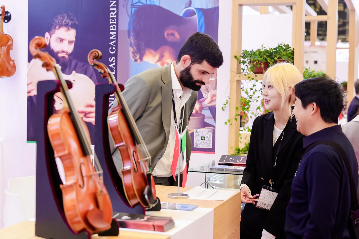Encontro entre visitantes e expositor de instrumentos de cordas na Music China 2025 Visitantes conversam com um expositor ao lado de violinos em exposição.